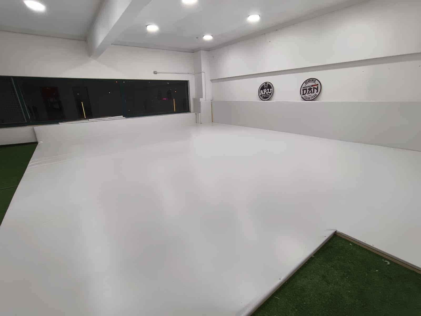Nuevo tatami blanco de COHAB, con los logos de la academia en la pared
